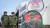 Руски војници стојат во близина на мобилен центар за регрутирање со постер со информации за плата во Ростов-на-Дон, Русија, март 2024 година