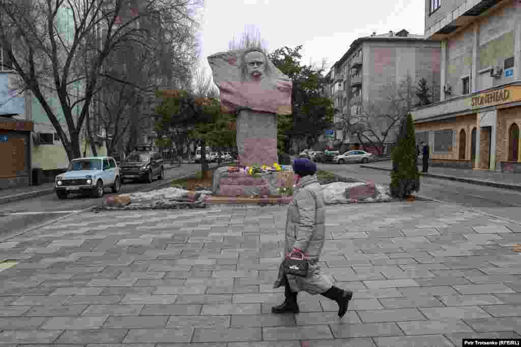 Женщина проходит мимо памятника Тарасу Шевченко, к которому люди только начали приносить цветы в память о погибших украинцах 