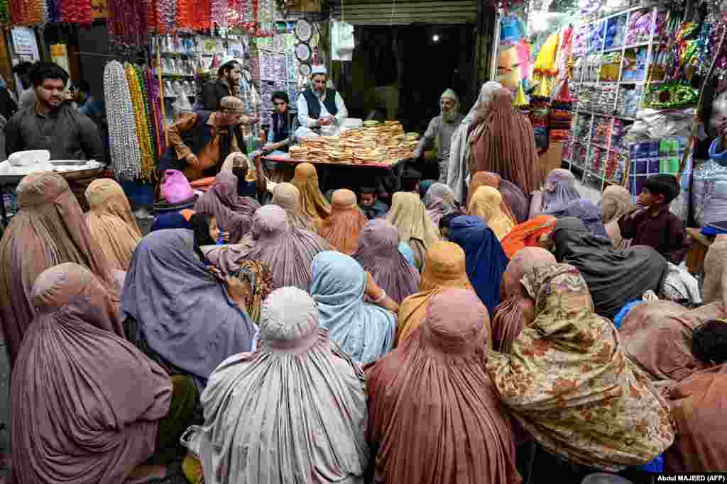 Femei îmbrăcate în burqa așteaptă pâine gratuită la un punct de distribuire a ajutoarelor în Peshawar, Pakistan.