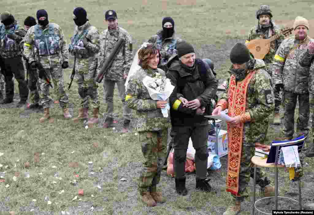 Леся Иващенко жана Валерий Филимонов, Украинанын аймактык коргонуу күчтөрүнүн аскерлери. Алар баш кошкондон кийин Киевге жакын блокпостто дин кызматкеринин насаатын угуп турган кези. 6-март.