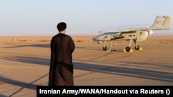 یک روحانی در جریان یک رزمایش نظامی در نقطهای نامعلوم از ایران رو به یک پهپاد ایستاده است