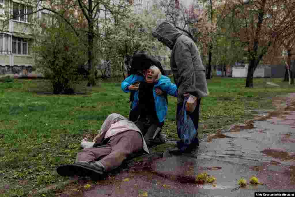Yana Bachek ngushëllohet nga partneri i saj, Yevhen Vlasenko, dhe nëna e saj, Lyubov Hubareva, teksa qan mbi trupin e babait të saj, Viktor Hubarev, 79 vjeç, i cili u vra nga sulmet në Harkiv më 18 prill 2022.