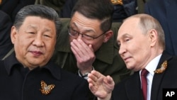 Президент Росії Володимир Путін та президент Китаю Сі Цзіньпін розмовляють під час перегляду військового параду до Дня Перемоги в Москві, Росія, 9 травня 2025 року