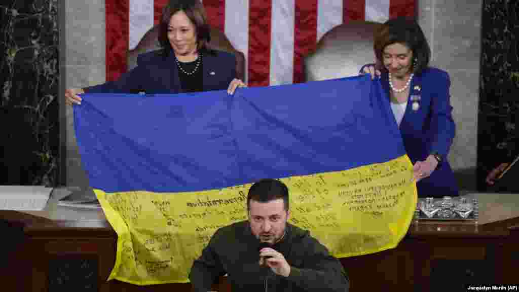 Volodimir Zelenszkij kongresszusi beszéde közben Kamala Harris amerikai alelnök (balra) és Nancy Pelosi akkori házelnök mutatja azt az ukrán zászlót 2022. december 21-én, amelyet a törvényhozóknak adott az ukrán elnök, és amelyen a Bahmutban szolgálatot teljesítő katonák aláírása szerepel