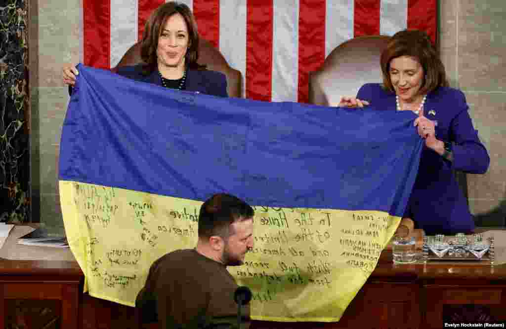 Харрис (слева) и спикер палаты представителей США Нэнси Пелоси держат украинский флаг, привезённый президентом Украины Владимиром Зеленским из Бахмута во время его выступления на совместном заседании Конгресса США 21 декабря 2022 года. «Бахмут стоит, — сказал Зеленский под аплодисменты. — Украина держит свои позиции и никогда не сдастся» 