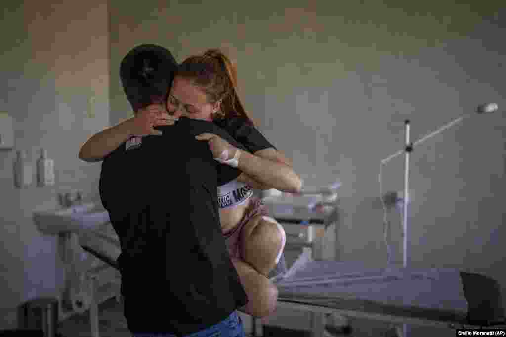 Oksana Balandina, 23 vjeç, bartet nga bashkëshorti i saj, Viktor, në një spital në Lviv më 13 maj 2022. Oksana humbi të dyja këmbët dhe katër gishtat e dorës së majtë kur një predhë shpërtheu pranë shtëpisë së saj. "Kishte një shpërthim. Ndjeva një zbrazëti në këmbët e mia menjëherë pas kësaj. Po përpiqesha të shikoja përreth dhe pashë se nuk kishte më këmbë -- vetëm kocka, mish dhe gjak", rikujton ajo.