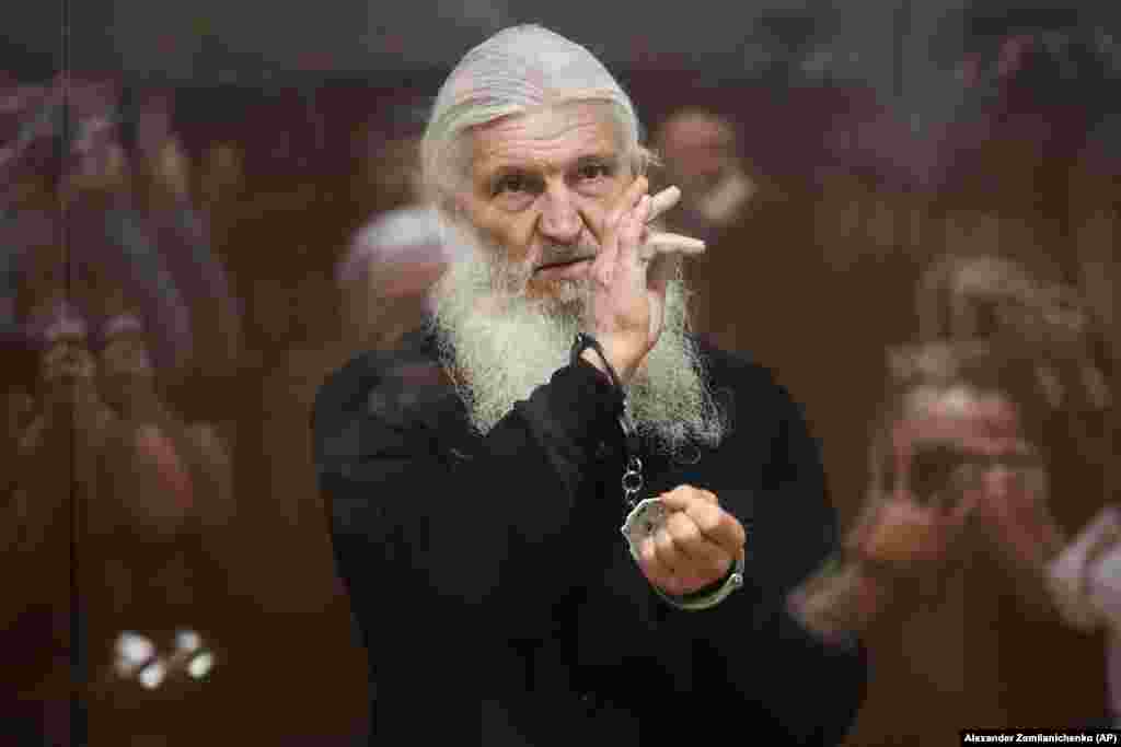 Nikolai Romanov, un fost călugăr cunoscut sub numele de Părintele Serghie (până la excomunicarea sa de Biserica Ortodoxă Rusă) îi binecuvântează pe cei prezenți în sală din cușca de sticlă în care a fost izolat pe timpul procesului său de la Moscova. Călugărul, care a negat existența coronavirusului și a sfidat Kremlinul, a primit o nouă condamnare la închisoare pe 27 ianuarie, fiind acuzat de incitare la ură.
