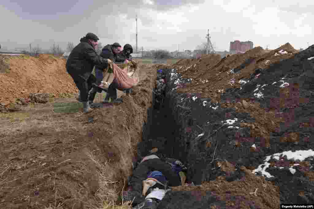 Украинанын Мариуполь шаары. Жергиликтүү жашоочулар сөөктөрдү боордоштор көрүстөнүнө таштап жатышат. Орусиялык күчтөрдүн тынымсыз аткылоосунан улам бул жердегилер маркумдарды көмө алышпайт. 9-март, 2022-жыл. 