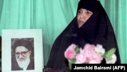 اعظم طالقانی در کنار تصویری از پدر خود، آیتالله محمود طالقانی