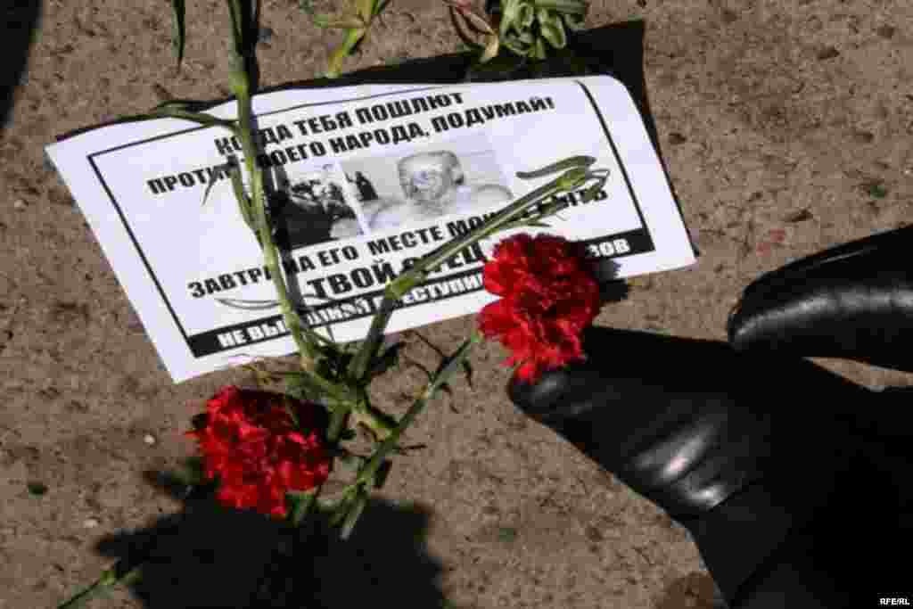Листовка и гвоздики под ногами у полицейских, которые не дают пройти демонстрантам. Алматы, 1 мая 2010 года.