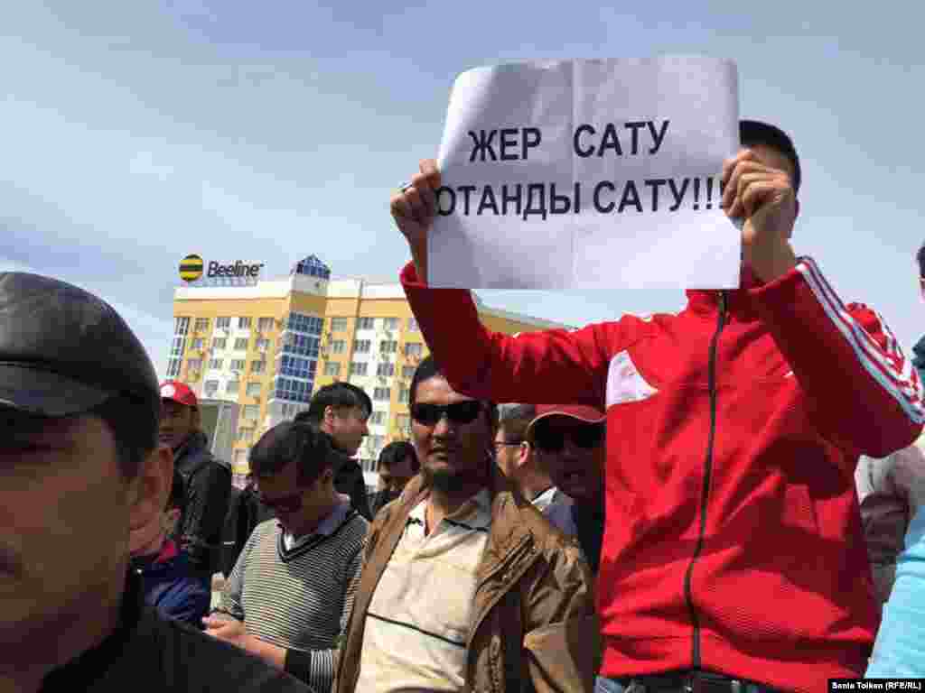 Участник митинга держит плакат с надписью: "Продать землю - значит продать родину".