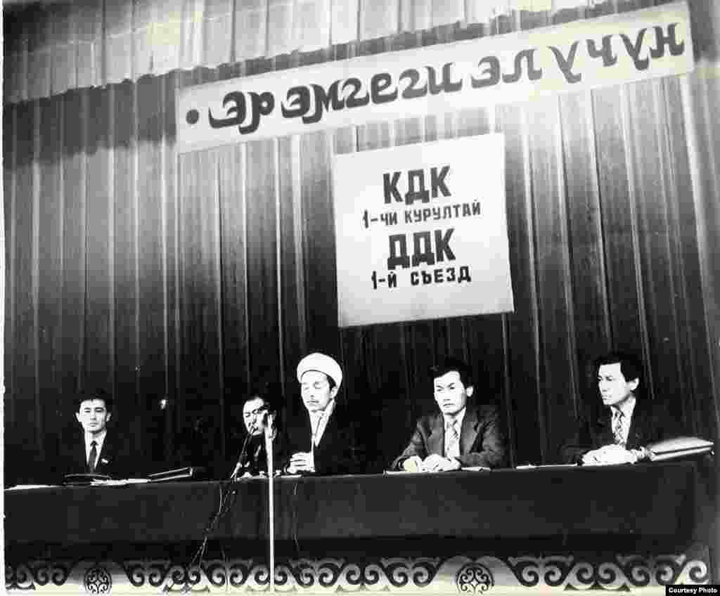"КДК"нын уюштуруу жыйынынан кийинки алгачкы курултайынын ачылышы. Бишкек ш., Кыргызстан. 09.2.1991. - 1991-жылдын 9-10-февралында өткөрүлгөн "Кыргызстан Демократиялык Кыймылынын ("КДК") Биринчи курултайынын ачылыш салтанаты маалында. Төрдө отургандар - Өмүрбек Текебаев, депутат жана КДКнын мүчөсү, Казат Акматов, депутат жана КДКнын теңтөрагасы, Дүйшөнбек Отонбай уулу, Кыргызстандын муфтийинин катчысы, Кадыр Матказиев, КДКнын теңтөрагасы, жана Жыпар Жекше, КДКнын теңтөрагасы (солдон оңго). (КДКП архивинен). 