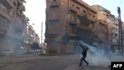 A protester throws a tear gas bomb back towards security forces in the flashpoint city of Homs.