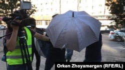 В Нур-Султане неизвестные чинят помехи сотрудникам Азаттыка с помощью зонтов, 6 июля 2019 года.