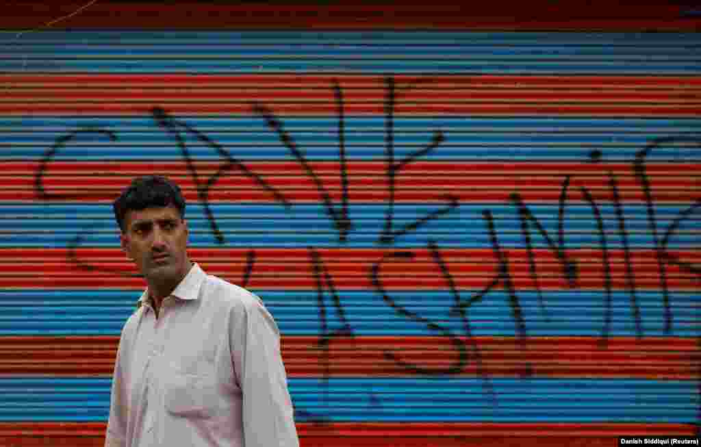 Një banor i Kashmirit duke ecur pranë një grafiti ku shkruan "Shpëtoje Kashmirin". Kryeministri pakistanez Imran Khan e krahasoi partinë qeverisëse të Indisë me nazizmin dhe shkroi në Twitter: "Ekziston një përpjekje për të ndryshuar demografinë e Kashmirit me anë të spastrimit etnik".