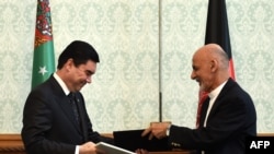 Afghan President Ashraf Ghani (R) exchanges documents with Turkmen President Gurbanguly Berdymukhamedov at the Presidential Palace in Kabul, in August.