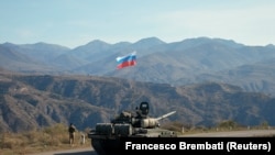 A service member of the Russian peacekeeping troops walks near a tank near the border with Armenia, following the signing of a deal to end the military conflict between Azerbaijan and ethnic Armenian forces