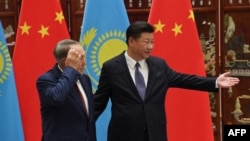 Chinese President Xi Jinping (R) gestures for Kazakh President Nursultan Nazarbaev to join him during their meeting at the West Lake State Guest House in Hangzhou on September 2