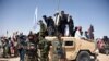 FILE: Afghan Taliban militants and residents stand on an armored Humvee vehicle of the Afghan National Army (ANA) as they celebrate a cease-fire in Maiwand district of Kandahar Province in June 2018.