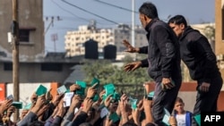 Palestinienii își arată cărțile de identitate pentru a primi rații de făină pentru familiile lor în fața unui depozit al Agenției Națiunilor Unite de Ajutor și Lucrări pentru Refugiații Palestinei (UNRWA) din Rafah. 12 decembrie.