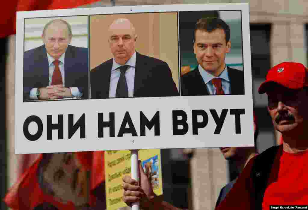 Акция в Москве против предложенной властями реформы, предусматривающей повышение пенсионного возраста. 2 сентября 2018 года. Активисты держат в руках плакат с изображениями Путина, Медведева и министра финансов Антона Силуанова с надписью: «Они нам врут».
