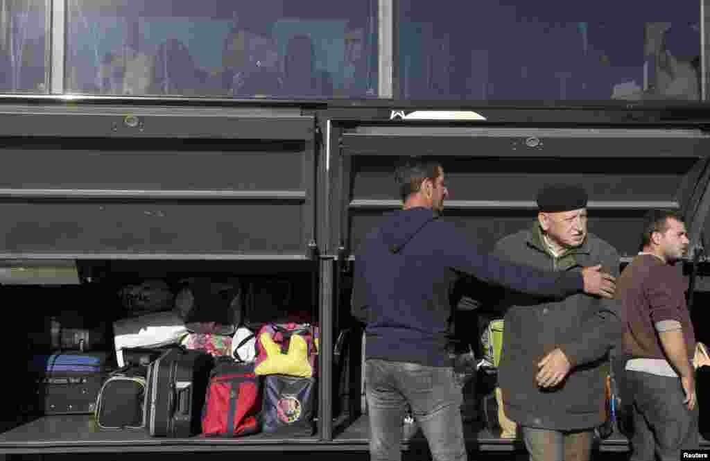 Udhëtarët ngarkojnë bagazhet e tyre në një autobus.