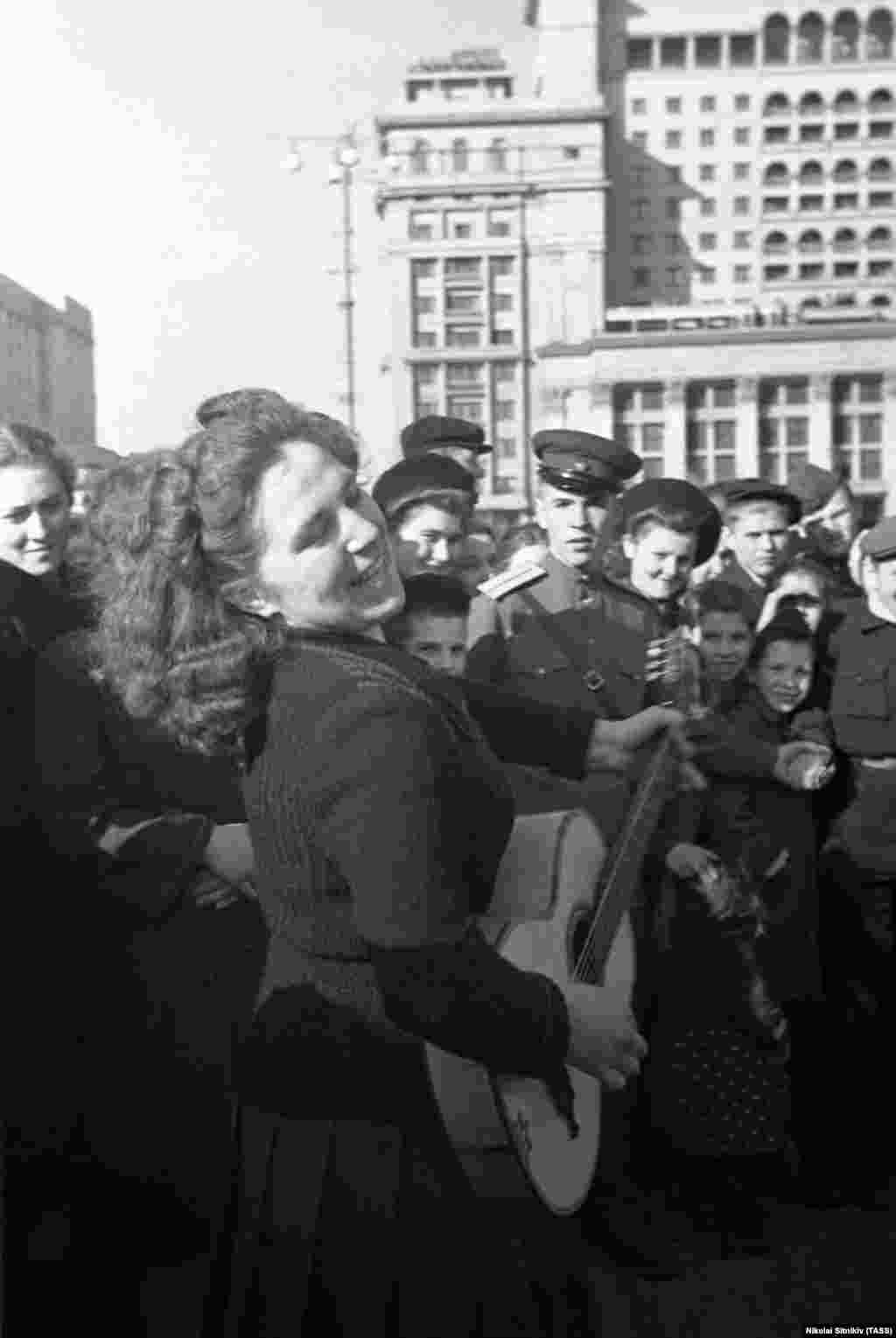 Жена свири гитара и пее во центарот на Москва на прославата за победата над фашизмот.