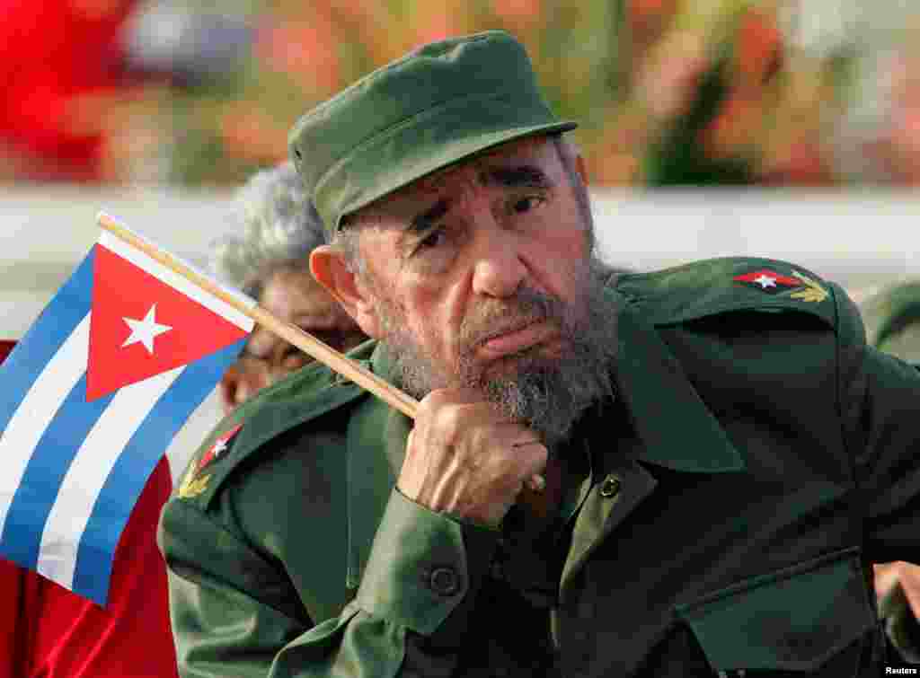 Duke mbajtur një flamur Kubës, Castro dëgjon një drejtues gjatë paradës Ditës së Majit në Sheshin e Revolucionit të Havanës, në vitin 2005.