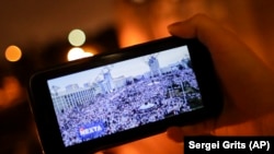 Човек го гледа каналот Телеграм НЕКСТА на својот паметен телефон во Минск, 19.08.2002 година