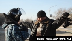 жаңаөзенде полиция қызметкері ер адамды тексеріп тұр. Жаңаөзен, 19 желтоқсан 2011 жыл.