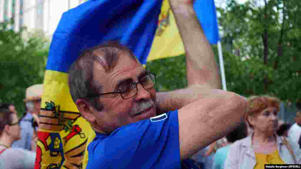 Un demonstrant își pune în spate drapelul național. 