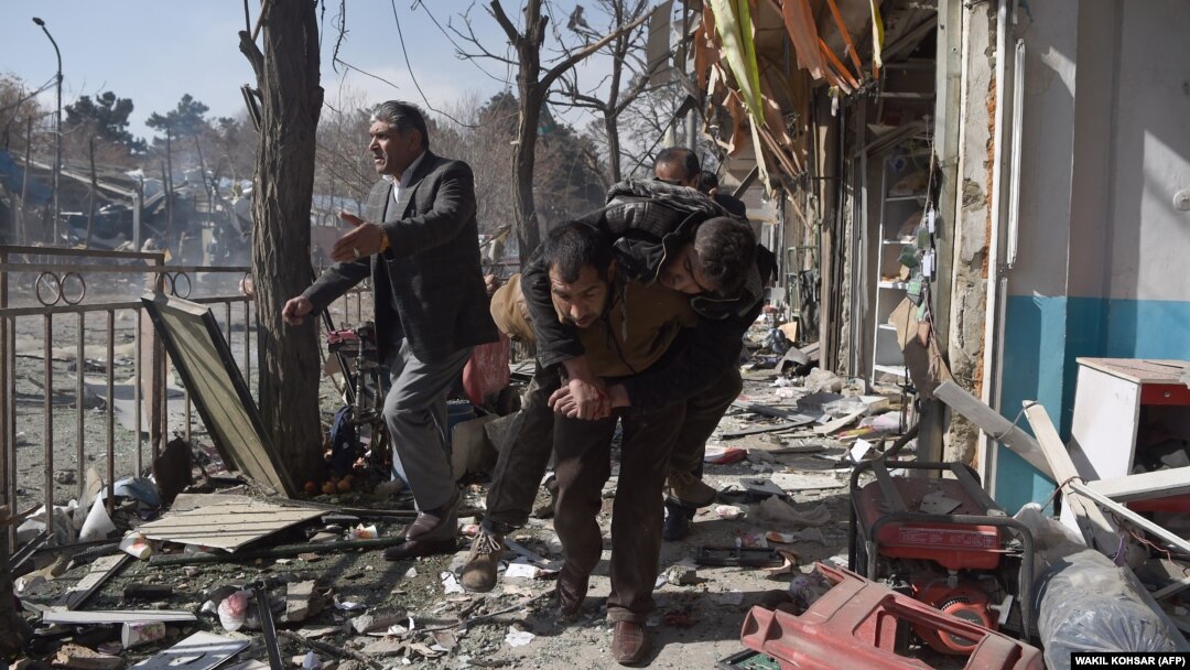Afghan volunteers carry a victim at the scene of a car bomb that exploded in front of the old Ministry of Interior building in Kabul on January 27.