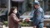 Armenia -- A police officer enforcing a coronavirus lockdown checks a woman's documents, Yerevan, March 25, 2020.