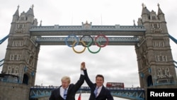 U.K. -- London Mayor Boris Johnson (L) and LOCOG Chairman Sebastian Coe pose for photos on a river boat under Tower Bridge after the the Olympic Rings were lowered into position for display in central London, 27Jun2012