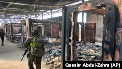 U.S. soldiers on January 13 walk past the site of where Iran bombed the Ain Al-Asad air base in Iraq.