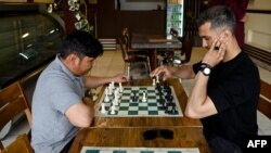 Men play chess at the Cupcake Coffee Shop cafe in Kabul On May 11.