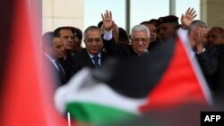 Palestinian president Mahmud Abbas waves to thousands of cheering Palestinians as they welcome their president at his Ramallah headquarters