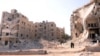 Syria -- People walk past a row of destroyed buildings near the Al-Hayat Hospital in the northern city of Aleppo, 10Sep2012