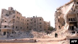 Syria -- People walk past a row of destroyed buildings near the Al-Hayat Hospital in the northern city of Aleppo, 10Sep2012