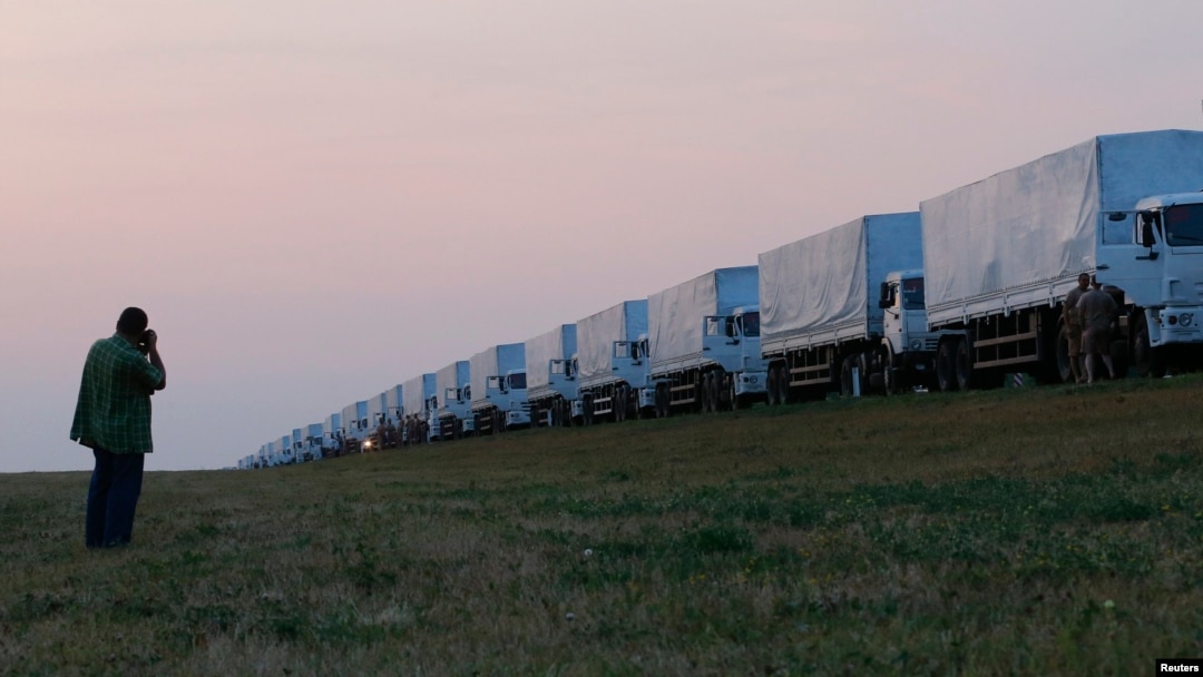 A man takes a picture of a Russian convoy of trucks carrying what Moscow says is humanitarian aid for Ukraine after the convoy stopped along a road near the Russian city of Yelets on August 12.