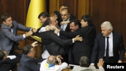 The speaker of Ukraine's parliament, Volodymyr Lytvyn (right), looks on as deputies scuffle during a session in the parliament chamber in Kyiv on May 24.