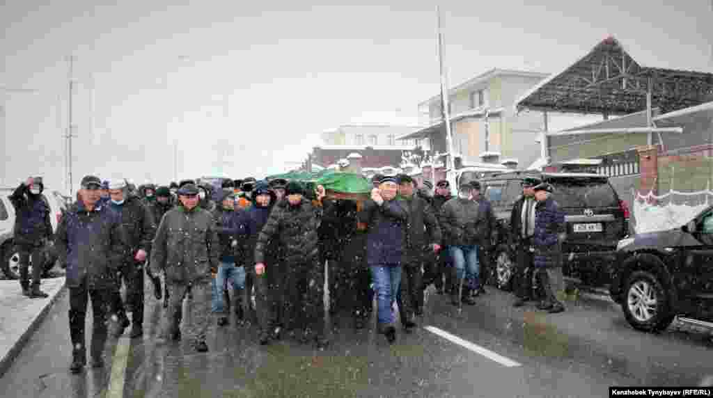 Марқұмның сүйегін көлікке салуға апара жатқан адамдар. 