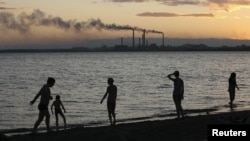Residents walk the shore of Lake Balkhash at dusk, in front of the city's 1930s-built copper smelter owned by Kazakhmys copper mining company in the city of Balkhash.