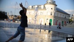 Një djalë 'freskohet' në fontanën në qendër të Prishtinës. Foto nga arkivi